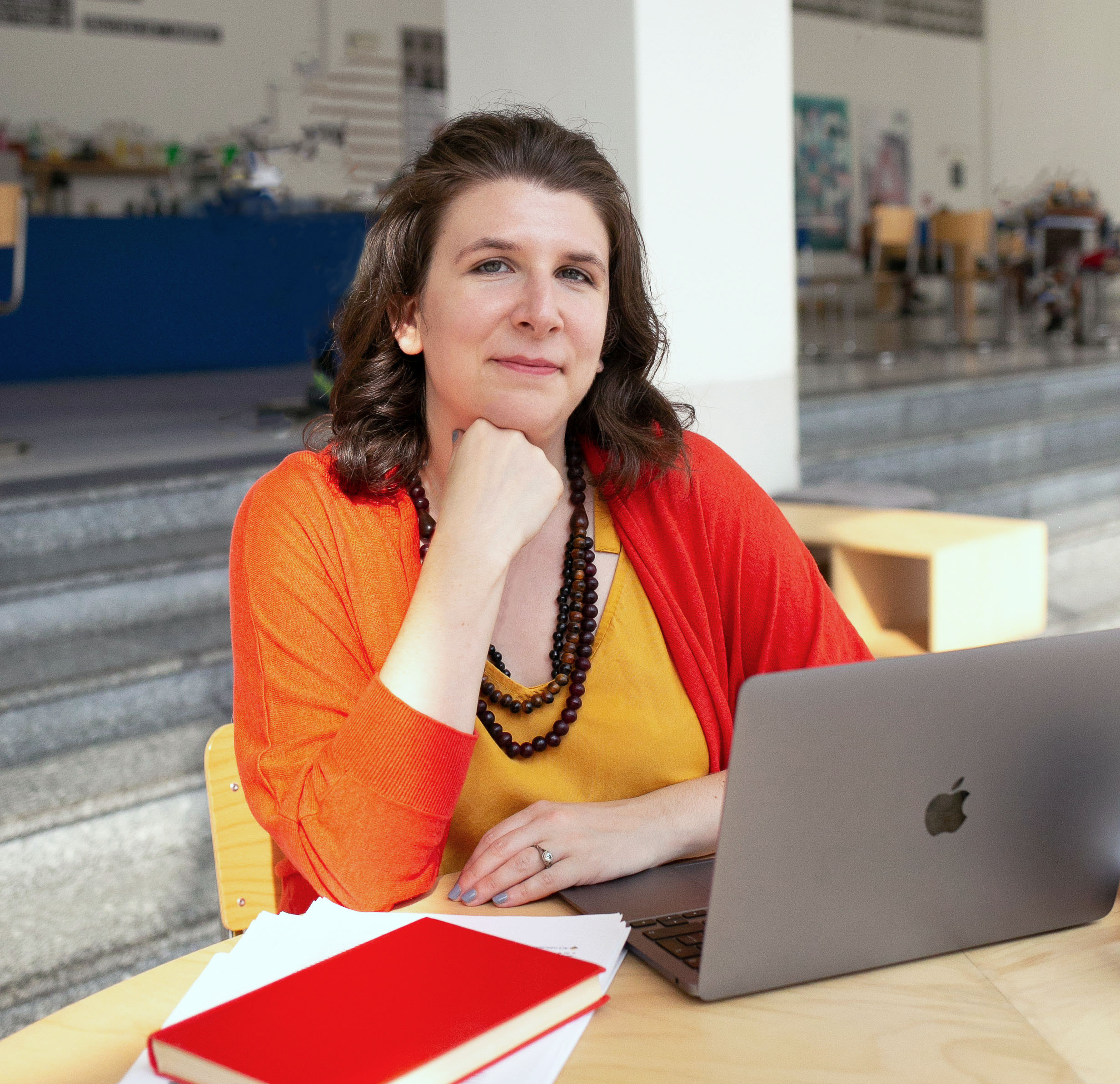 Dr Anna Clemens smiling while working at a laptop in between the Researchers' Writing Academy assistants Andrea Frye and Yvonne Rimar